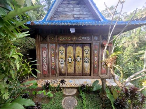 a wooden gate to a house in a garden at Villa Batari - Artsy Joglo - Private Swimming Pool in Tegalalang