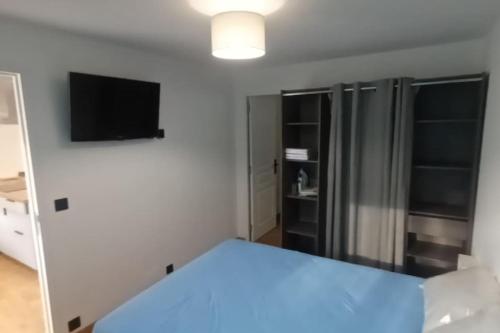 - une chambre avec un lit bleu et une télévision dans l'établissement Appartement calme, à Salses-le-Chateau