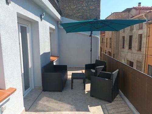 d'une terrasse avec des chaises et un parasol sur le balcon. dans l'établissement Appartement calme, à Salses-le-Chateau