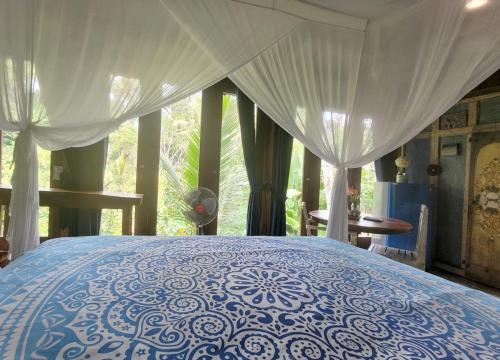 a blue and white bed in a room with a window at Villa Batari - Artsy Joglo - Private Swimming Pool in Tegalalang