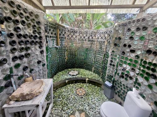 a bathroom with a toilet and a wall of wine bottles at Villa Batari - Artsy Joglo - Private Swimming Pool in Tegalalang