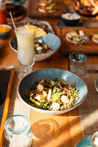 a table with a bowl of salad and a glass of milk at Samawa Living in Paje