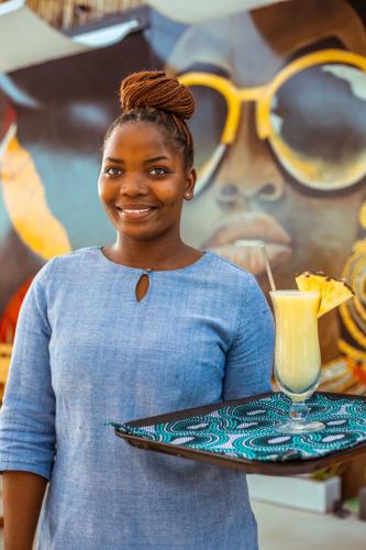 a woman holding a tray of food and a drink at Samawa Living in Paje