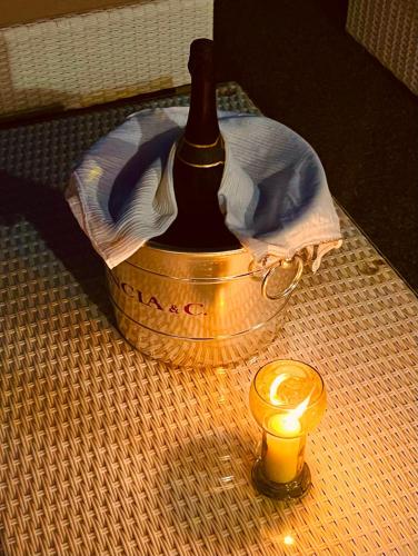 a bottle of wine in a bucket next to a candle at Appartamento Rapallo Sky Garden Maria Jose Liguria - Attico vista mare - Terraces - 2 bagni- 2 Camera da Letto - Box, Wi-fi, Idromassaggio Free inteiro Attico per Voi, con Ascensore in Rapallo