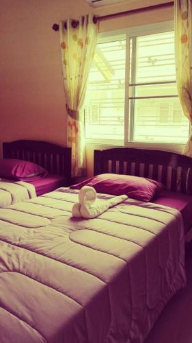 a teddy bear sitting on a bed in a bedroom at Lampang Lanna Home in Lampang