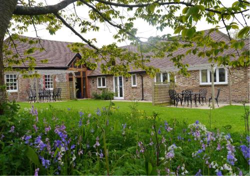 a brick house with flowers in the yard at Cottages by the Moat in Hassocks