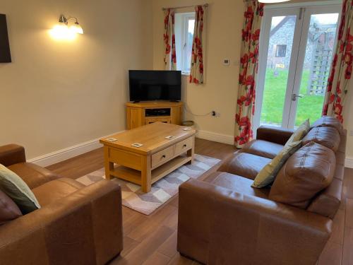 a living room with two couches and a television at Cottages by the Moat in Hassocks