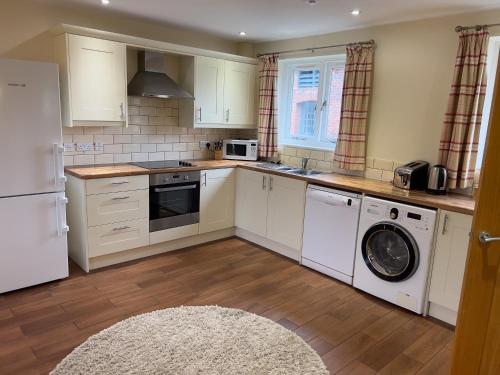 a kitchen with white cabinets and a washer and dryer at Cottages by the Moat in Hassocks
