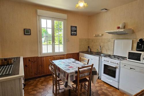 une cuisine avec une table et une cuisinière four supérieur dans l'établissement La Maison Bricquebetaise, à Bricquebec