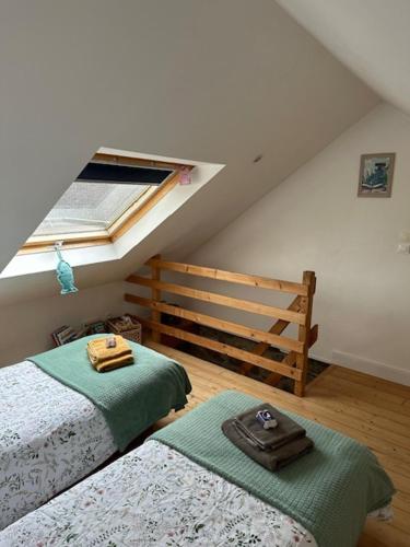 - une chambre mansardée avec 2 lits et une fenêtre dans l'établissement jolie maisonnette proche plage et activités nautiques, à Ploudalmézeau