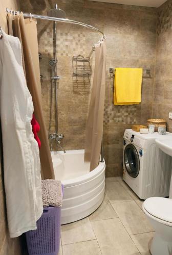 a bathroom with a tub and a washing machine at Apartment Antiokia in Mtskheta