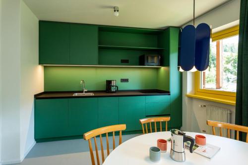 a kitchen with green cabinets and a table with chairs at MiraOdle Apartments in Villnoss