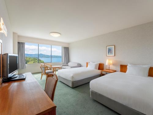 Una habitación de hotel con dos camas y un escritorio. en Mercure Kyoto Miyazu Resort & Spa, en Miyazu
