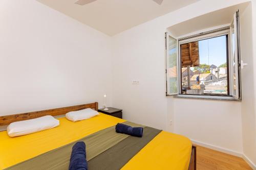 a bedroom with a yellow bed and a window at Old Charming House in Lastovo
