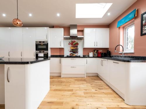 a kitchen with white cabinets and a wooden floor at 4 Bed house Parking 5 mins Sidcup Station - Pass the Keys in Sidcup