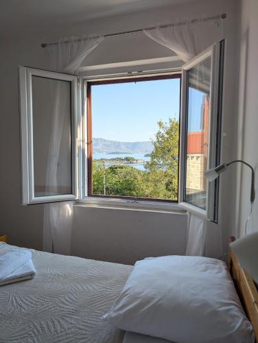 a bedroom with a bed and a large window at Apartments Ante in Lumbarda