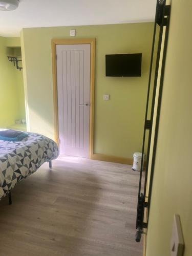 a bedroom with a bed and a door with a television at Tumbledown Hotel in Shrewsbury