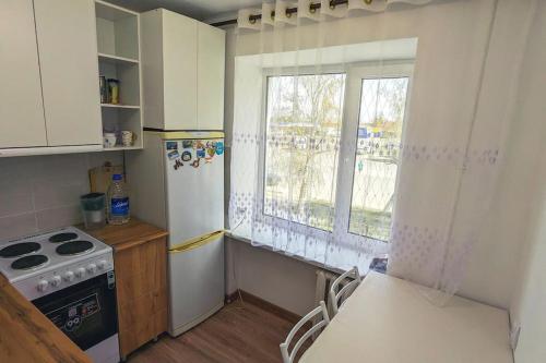 a kitchen with a stove and a refrigerator and a window at Cozy apartment in the city center of Karakol in Karakol