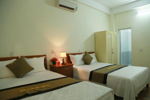 a hotel room with two beds and a lamp at Gold Plus hotel in Phong Nha