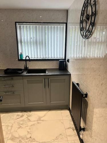 a kitchen with a sink and a clock on the wall at Modern 2 bedroom apartment in Nantwich