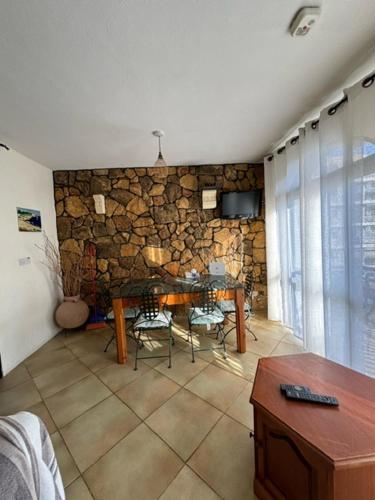 a living room with a table and a stone wall at Cozy beachside in Xlendi