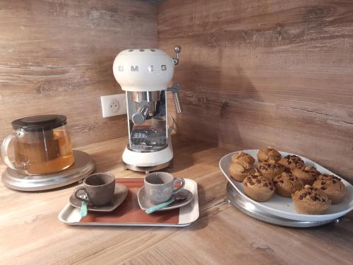 Una cafetera y un plato de muffins sobre una mesa en Chambre d'hôte chez Nicole et Pierre, en Eyragues