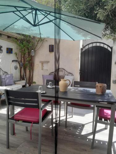 une table et des chaises avec un parasol sur une terrasse dans l'établissement Chambre d'hôte chez Nicole et Pierre, à Eyragues