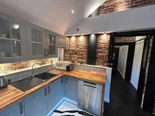 une cuisine avec des placards bleus et un mur en briques dans l'établissement Loft de standing, à Cholet