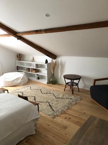 a bedroom with a bed and a table and a rug at LA PARENTHÈSE in Saubrigues