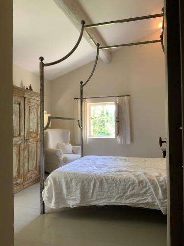 une chambre avec un lit à baldaquin et une chaise dans l'établissement La Cour Intérieure Ménerbes, à Ménerbes