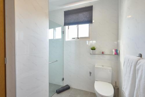 a white bathroom with a toilet and a shower at Apartments in La Julia 1 and 2 Bedrooms in Santo Domingo