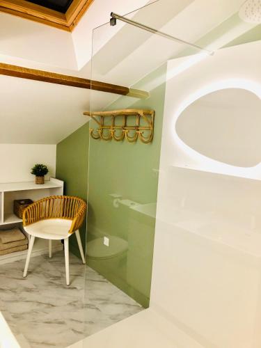 a bathroom with a glass shower and a chair at LA PARENTHÈSE in Saubrigues