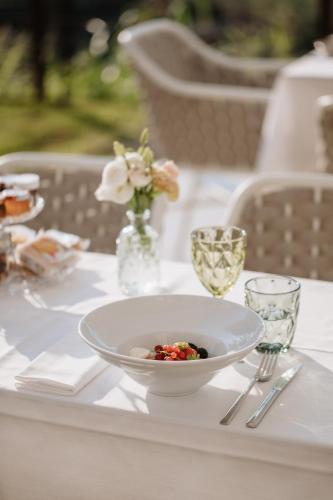 a table with a white bowl on a table with glasses at Boutique Hotel Municipio 1815 in Valdobbiadene