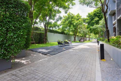 a sidewalk with benches and trees in a park at Panoramic Pool at The Valley in Pak Chong