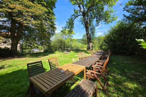 une rangée de tables et de chaises en bois dans la pelouse dans l'établissement Villa de luxe, nichée dans les montagnes, à Lavoine