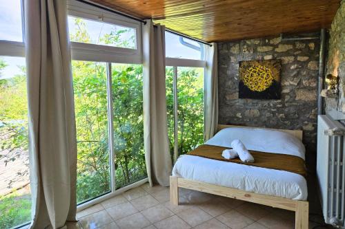 ein Schlafzimmer mit einem Bett in einem Zimmer mit Fenstern in der Unterkunft Villa de luxe, nichée dans les montagnes in Lavoine