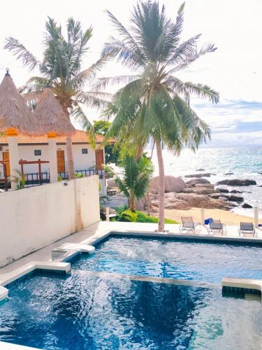 a swimming pool with palm trees and the ocean at Simple Life Talay & Divers Resort in Koh Tao