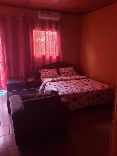 a bedroom with a bed and a window with red curtains at Diaspo Meublés in Yaoundé