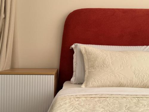a bed with a red headboard and a white pillow at EXPO Premium in Prigorodnyy