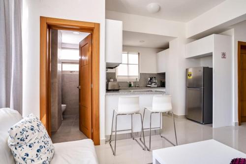 a kitchen with a refrigerator and two bar stools at Apartments in La Julia 1 and 2 Bedrooms in Santo Domingo