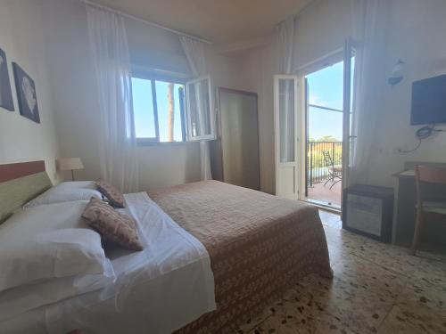 a white bedroom with a bed and a large window at Hotel Villa Tiziana in Marina di Pietrasanta