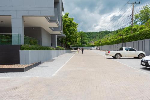 two people walking down a sidewalk next to a building at The Valley at Sunshine, Panoramic in Pak Chong