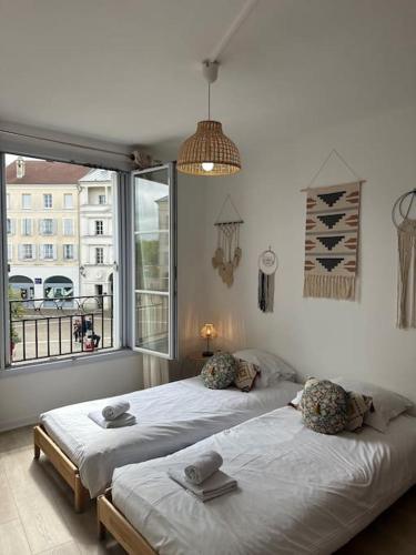 deux lits dans une chambre avec une grande fenêtre dans l'établissement Place Toscane Appartement Long séjour, à Marne-la-Vallée