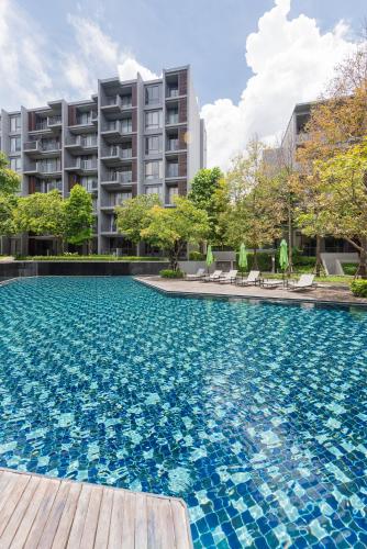 a swimming pool with blue tiles in front of a building at The Valley at Sunshine, Panoramic in Pak Chong