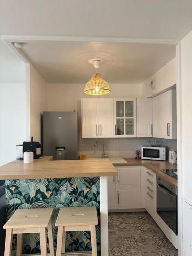 - une cuisine avec un comptoir et deux tabourets dans l'établissement Place Toscane Appartement Long séjour, à Marne-la-Vallée