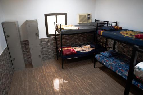 a room with four bunk beds and a mirror at Blue Wave Home in Al Bustān