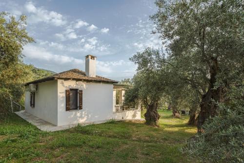 a small white house in a field with trees at Aeolos Hotel & Villas - Pelion in Chorefto
