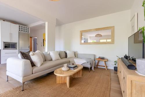 a living room with a white couch and a table at Stylish and Spacious Beach Apartment in Sydney