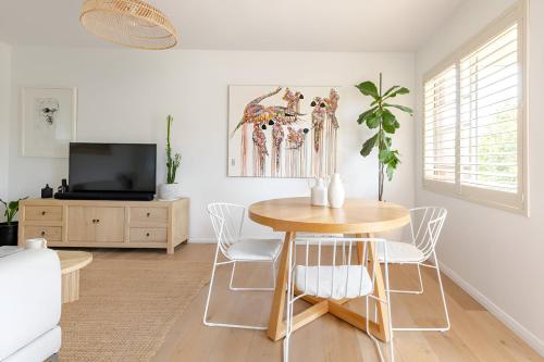 a dining room with a table and chairs and a tv at Stylish and Spacious Beach Apartment in Sydney