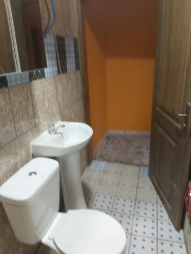 a bathroom with a white toilet and a sink at Diaspo Meublés in Yaoundé